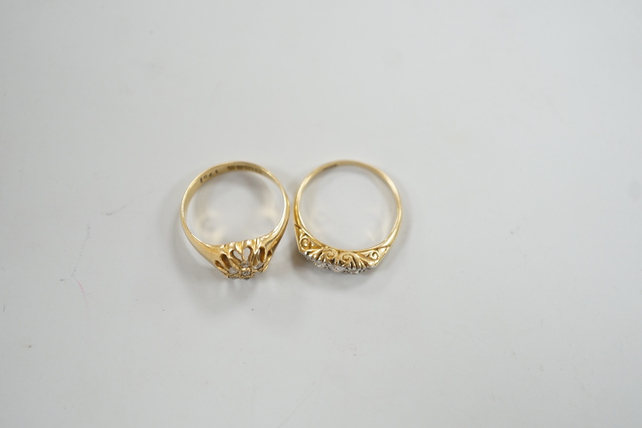 Two early 20th century 18ct and diamond cluster set rings, including graduated five stone, sizes M, gross weight 6.2 grams.